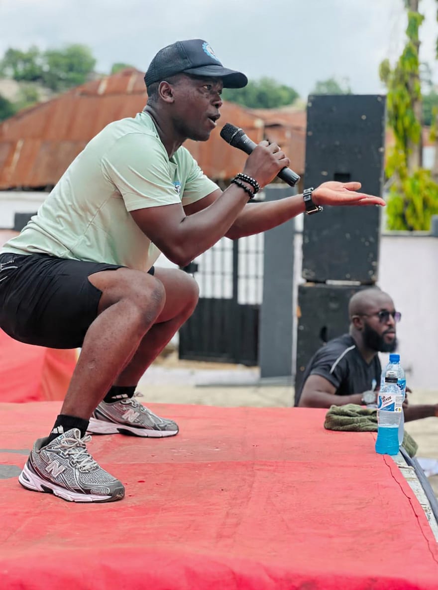 Coach Korede leading a fitness session with a microphone