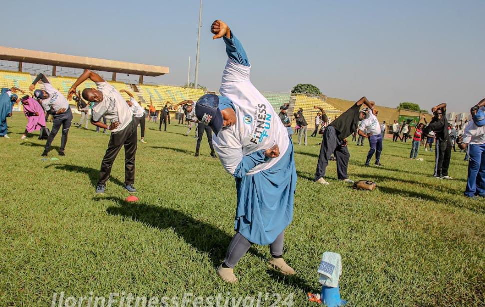 Participants performing side stretches during a stadium fitness session